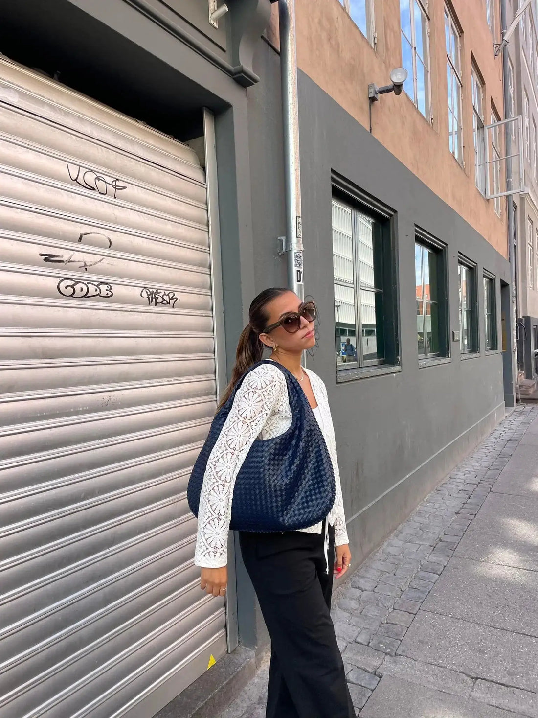 Vrouw met ovale marineblauwe schoudertas tijdens citytrip in Düsseldorf – stijlvolle crossbody tas voor stedentrips