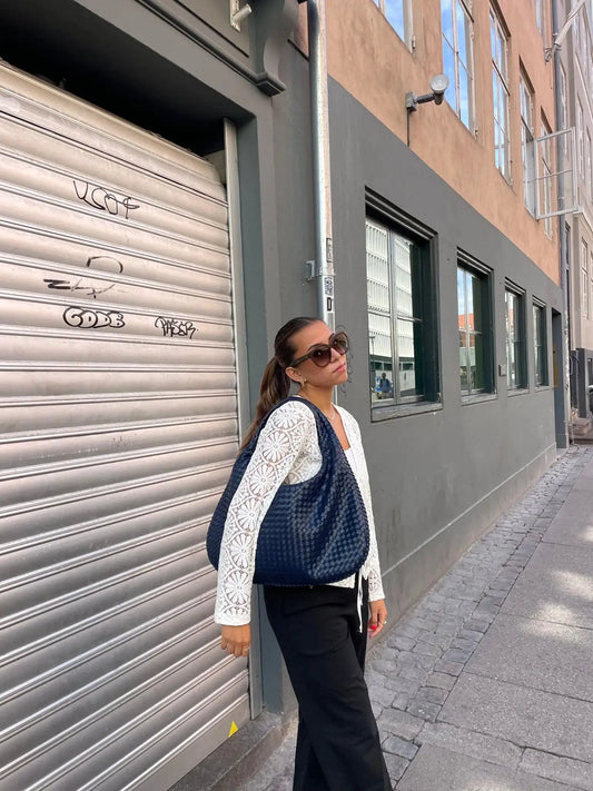 Vrouw met ovale marineblauwe schoudertas tijdens citytrip in Düsseldorf – stijlvolle crossbody tas voor stedentrips