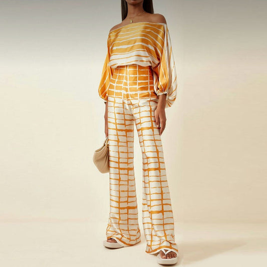 Model draagt Elysia satin co‑ord: satijnen off‑shoulder top en wijde broek met hoge taille in luxe satijnlook | Becker’s Amsterdam